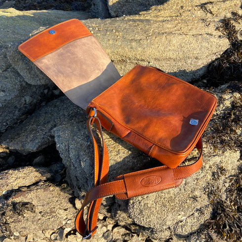 The Floto Siena leather shoulder sling bag is a men's messenger bag that is handcrafted in Italy. This is the Siena Field Bag in Olive Honey Brown - beach 3